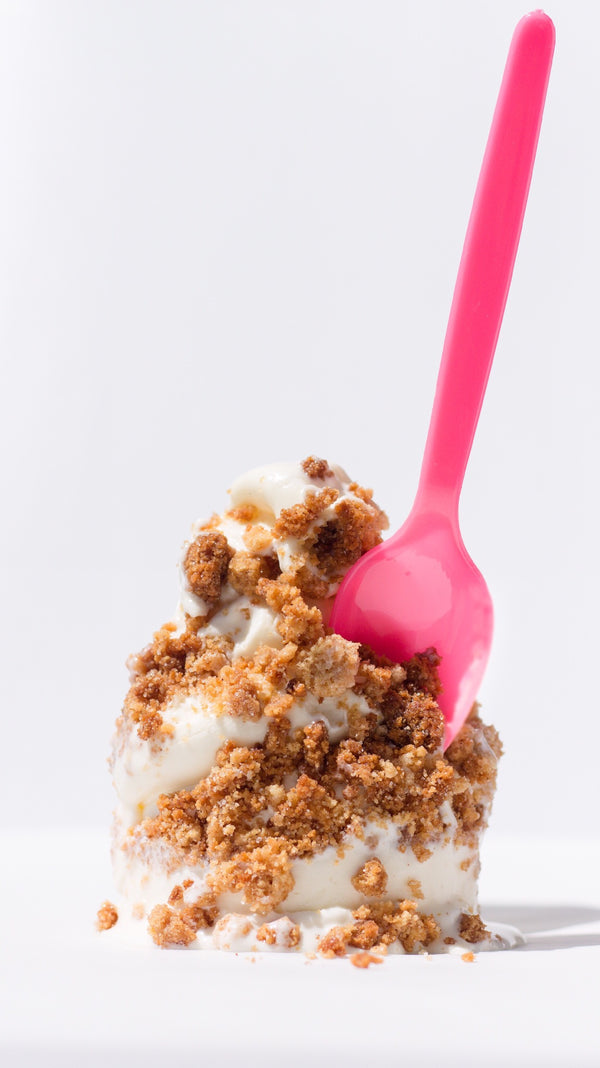 Churro cake crunch topping scattered over vanilla ice cream with a pink spoon